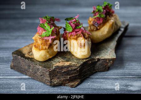 Closeup köstliche Mayan-Polkane-Gericht mit Kürbiskernen und weißen Bohnen Toksel garniert mit eingelegten roten Zwiebeln und Petersilie und serviert auf einem Stück Ro Stockfoto