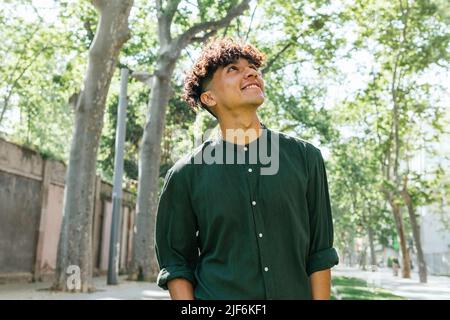 Das junge Männchen blickt weg, während es am hellen Sommertag auf einem grasbewachsenen Pfad im Stadtpark steht Stockfoto