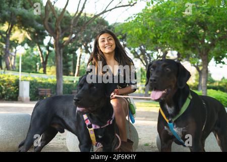 Charmante junge Zahnärztin in weißer Uniform lächelt und steht mit gefalteten Armen in einer modernen Klinik, während sie die Kamera anschaut Stockfoto