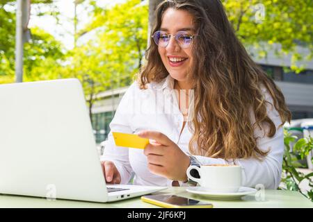 Konzentrierte junge weibliche Floristin in Schürze und Brillen Anordnung duftend Gelbe Mimosen Blumen in Vase während der Arbeit in Blumengeschäft Stockfoto