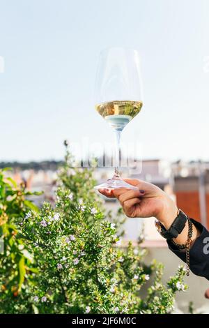 Nicht erkennbare Frau, die während der Verkostung auf der Restaurantterrasse einen Glaskelz mit Weißwein vorführt Stockfoto