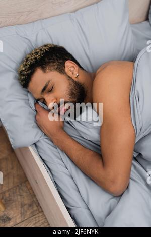 Blick aus der Perspektive auf einen bärtigen afroamerikanischen Mann mit geschlossenen Augen, der im Bett schlief Stockfoto