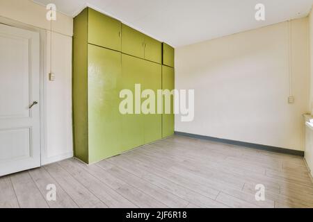 Vintage bunt grünen Kleiderschrank in geräumigen leeren Raum mit weißen Wänden und Holzboden Stockfoto