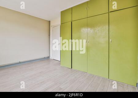 Vintage bunt grünen Kleiderschrank in geräumigen leeren Raum mit weißen Wänden und Holzboden Stockfoto