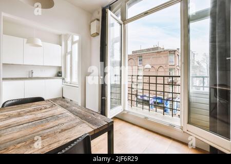 Home Interior Design der modernen Loft-Wohnung mit offener Küche In minimalistischem Stil und geräumiger Essecke mit Tisch und Stühle Stockfoto