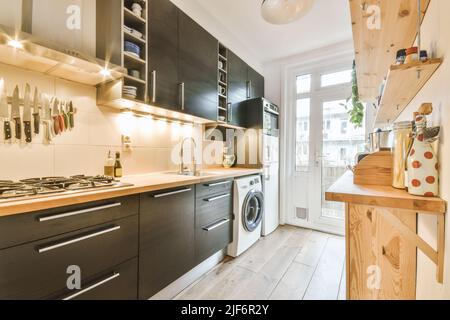 Offene Küche mit Schränken aus dunklem Holz und Pendelleuchten in luxuriösem Apartment Stockfoto