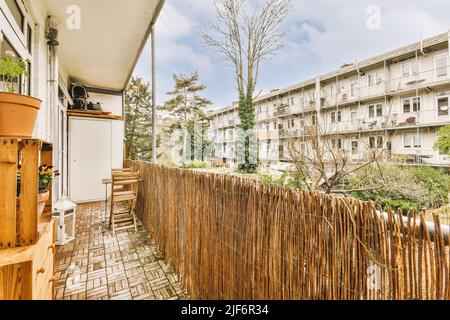 Enger Balkon mit Holzgeländer mit Stuhl und Tisch in der Nähe von Blumentöpfen Stockfoto