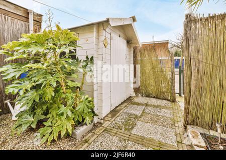 Gepflegte gepflasterter Innenhof mit Sitzecke und kleinem Garten in der Nähe von Holzzaun Stockfoto