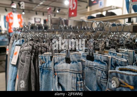 Viele Jeans in verschiedenen Farben hängen an Kleiderbügeln im Laden. Konzept für Kauf, Verkauf, Einkauf und Denim-Mode. Stockfoto