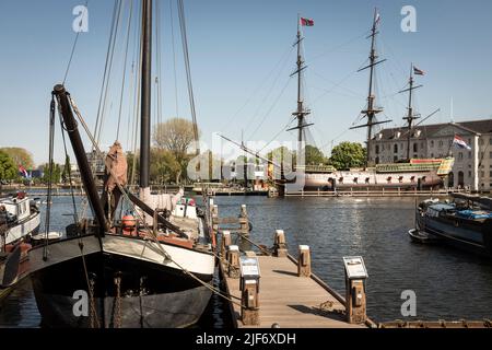 Eine Nachbildung einer Vereenigde Oostindische Compagnie, Dutch East India Company, Schiff, der Amsterdam, vor dem Het Scheepvaartmuseum, dem National Maritime Museum, mit einem historischen Handelsschiff im Vordergrund, den Niederlanden, in Amsterdam. Stockfoto
