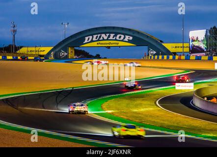 Rennwagen fahren nachts über die Dunlop-Schikane, bevor sie während der 24 Stunden von Le Mans unter der Dunlop-Fußgängerbrücke auf dem Circuit de la Sarthe fahren. Stockfoto