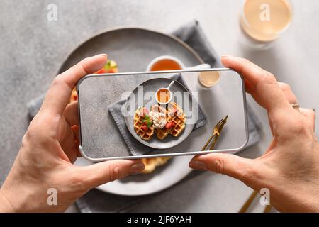 Frau machen ein Foto aus Frühstück mit Koffern und Kaffee mit dem Smartphone. Nahaufnahme. Stockfoto