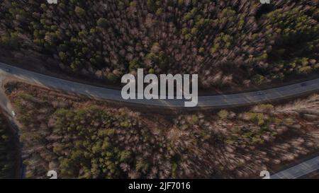 Kurve der Autobahn-Straße zwischen tiefen Wald in Ural, Russland. Schöne herbstliche Naturlandschaft bei tagsüber. Luftaufnahme von einer Drohne Stockfoto