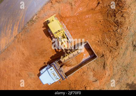 Schwere Baumaschinen arbeiten mit der Verladung der Erde in den Muldenkipper über einen Bagger Stockfoto