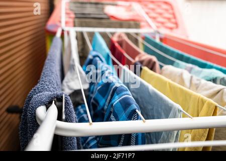 Saubere Kleidung wird nach dem Waschen durch Aufhängen an Wäscheleinen, auf einem speziellen Trockner, in Innenräumen getrocknet. Stockfoto