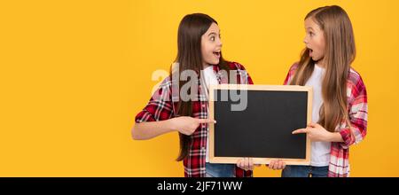 Schule Mädchen Freunde. Überraschte Kinder in lässig kariert zeigt Schule Tafel für Kopie Raum, Schulverkauf. Banner der Schülerin Stockfoto