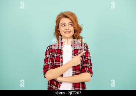 Frohes Rothaarige Frau im karierten Hemd mit Zeigefinger auf blauem Hintergrund Stockfoto