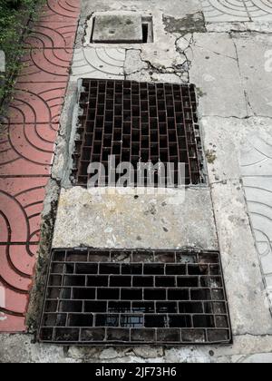 Die Metallschachtabdeckung auf dem Bürgersteig in der Nähe der Straße in der Stadt, Vorderansicht mit dem Kopierraum. Stockfoto