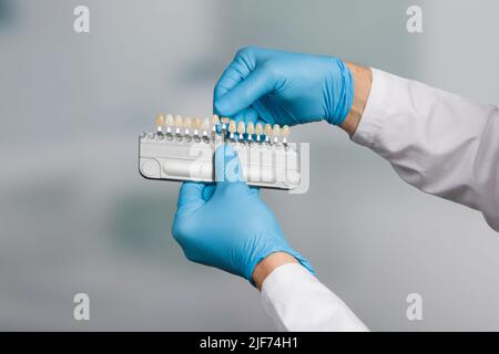 Zahnarzthand mit Farbführung zur Überprüfung/Bestimmung des Furniers der Zähne in der Zahnmedizin Stockfoto