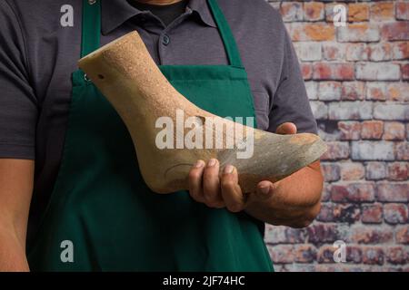 Nahaufnahme eines Schuhmachers, der eine individuelle Holzschnur zeigt, um einen individuellen Schuh zu erstellen Stockfoto