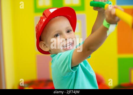 Ein kleiner Junge in einem Schutzhelm spielt einen Baumeister. Stockfoto