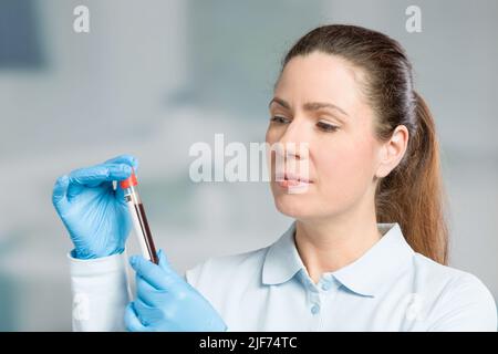 Krankenschwester oder Wissenschaftlerin führt in einem Labor eine Blutprobe in einem Reagenzglas durch Stockfoto