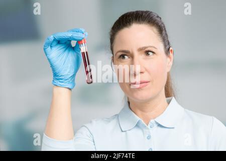 Krankenschwester oder Wissenschaftlerin führt in einem Labor eine Blutprobe in einem Reagenzglas durch Stockfoto