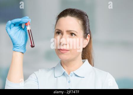 Krankenschwester oder Wissenschaftlerin führt in einem Labor eine Blutprobe in einem Reagenzglas durch Stockfoto