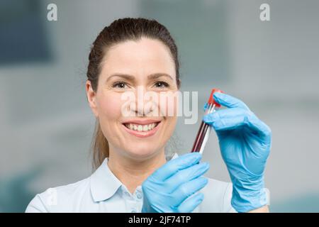 Krankenschwester oder Wissenschaftlerin führt in einem Labor eine Blutprobe in einem Reagenzglas durch Stockfoto