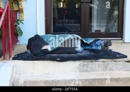 Obdachloser Mann schläft auf Stufen. Stockfoto