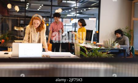 Kaukasische junge Geschäftsfrau, die am Schreibtisch im Büro am Laptop arbeitet Stockfoto