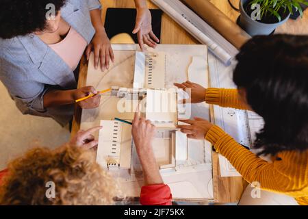 High-Angle-Ansicht von multirassischen Architekten, die im Büro über Architekturmodelle diskutieren Stockfoto