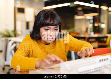 Biracial yfemale Architektin untersucht Architekturmodell in kreativen Büro Stockfoto