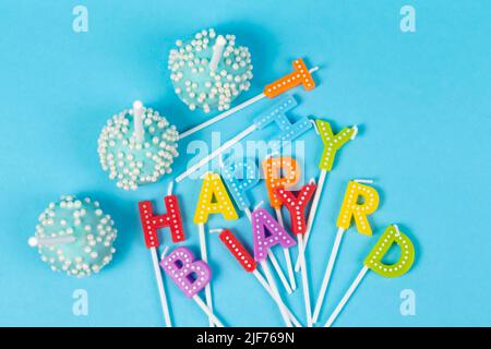 Kuchen mit regenbogenfarbenen Geburtstagskerzen mit der Aufschrift 'Happy Birthday' Stockfoto