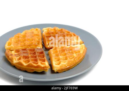 Weiche Muffin-Waffeln, gegossen mit frischem Honig in Teller auf weißem Hintergrund Stockfoto