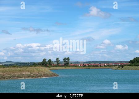 Das Ufer des Flusses Arun, in der Nähe von Littlehampton West Sussex. Zeigt Fluss bei Flut und neue Wohnsiedlung in Littlehampton in der Ferne Stockfoto