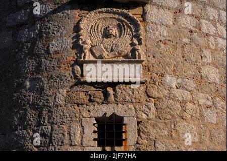 Tafel mit dem Emblem von Venedig, dem geflügelten Löwen des Heiligen Markus, auf einem runden Turm an einer Ecke der mittelalterlichen Burg in Krk, Insel Krk, Kroatien. Die Burg wurde von der kroatischen Frankopanerfamilie oder der französischen Familie erbaut und der Turm stammt wahrscheinlich aus den 1200s Jahren. Diese Tafel wurde jedoch in das Steinwerk eingesetzt, als Venedig den Turm 1500 umbaute. Die lateinische Inschrift unter dem Emblem „Aureae Venetorum Libertati“ bedeutet übersetzt „die Goldenen Freiheiten von Venedig“. Stockfoto