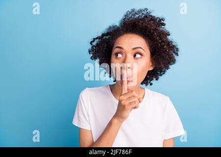 Portrait von attraktiven Brünette geheimnisvolle Mädchen zeigt shh Zeichen kopieren Raum isoliert über hellen blauen Hintergrund Stockfoto