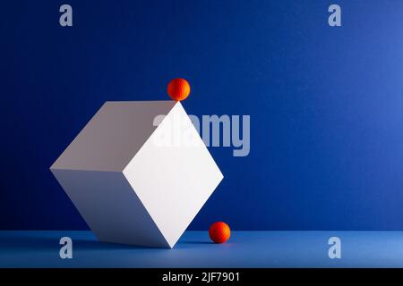 Zwei Würfel mit orangefarbenen Golfbällen auf dem blauen Hintergrund. Kreatives Bild. Stockfoto