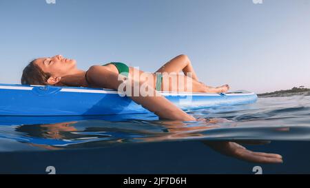 Mädchen sonnen sich auf dem Surfbrett im Meer Stockfoto
