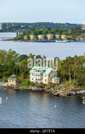 Hotel am Wasser auf einer der vielen Inseln des Stockholmer Archipels - hier Granholmen, Schweden. Dahinter befinden sich alte Öltanks auf Stora Hoggarn. Stockfoto