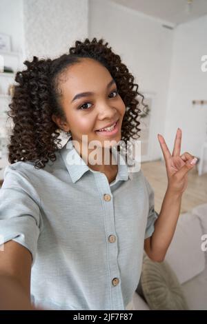 Junge glücklich afroamerikanischen Teenager-Mädchen halten Telefon Blick auf mobile Kamera. Stockfoto