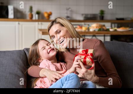 Glücklich Mutter empfangen Muttertag Geschenk-Box umarmt Kind Tochter zu Hause. Stockfoto