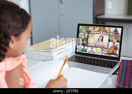 Asiatische Mädchen mit Buch und Bleistift Teilnahme Online-Klasse über Laptop auf dem Tisch zu Hause Stockfoto