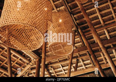 Hängende handgewebte Bambuskörbe unter dem cogon-Dach, hergestellt in Licht- oder Lampenschirmen zur Dekoration und zum Ambiente. Selektiver Fokus. Stockfoto