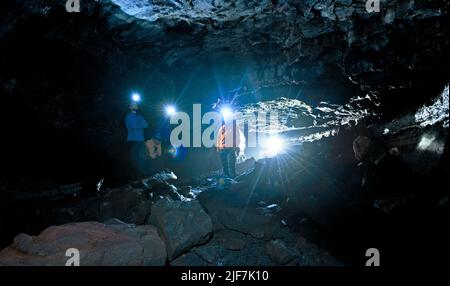 Gruppe von Wissenschaftlern, die die Lavahöhle Leidarendi in Island erkunden Stockfoto