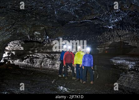 Gruppe von Wissenschaftlern, die die Lavahöhle Leidarendi in Island erkunden Stockfoto