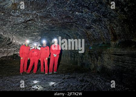 Gruppe von Wissenschaftlern, die die Lavahöhle Leidarendi in Island erkunden Stockfoto