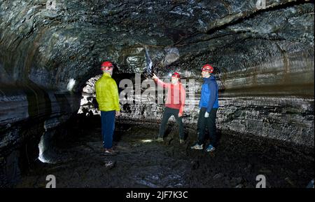 Gruppe von Wissenschaftlern, die die Lavahöhle Leidarendi in Island erkunden Stockfoto