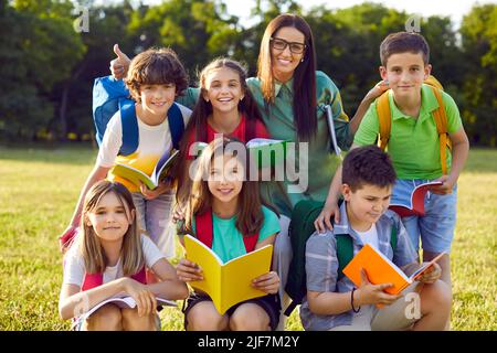 Gruppenportrait von glücklichen Schulkindern zusammen mit ihrem Lehrer während des Spaßunterrichtete draußen Stockfoto